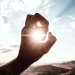 Doigts d'une main encerclant le soleil. Les rayons du soleil passent entre les doigts symbolisant le Soleil en astrologie.